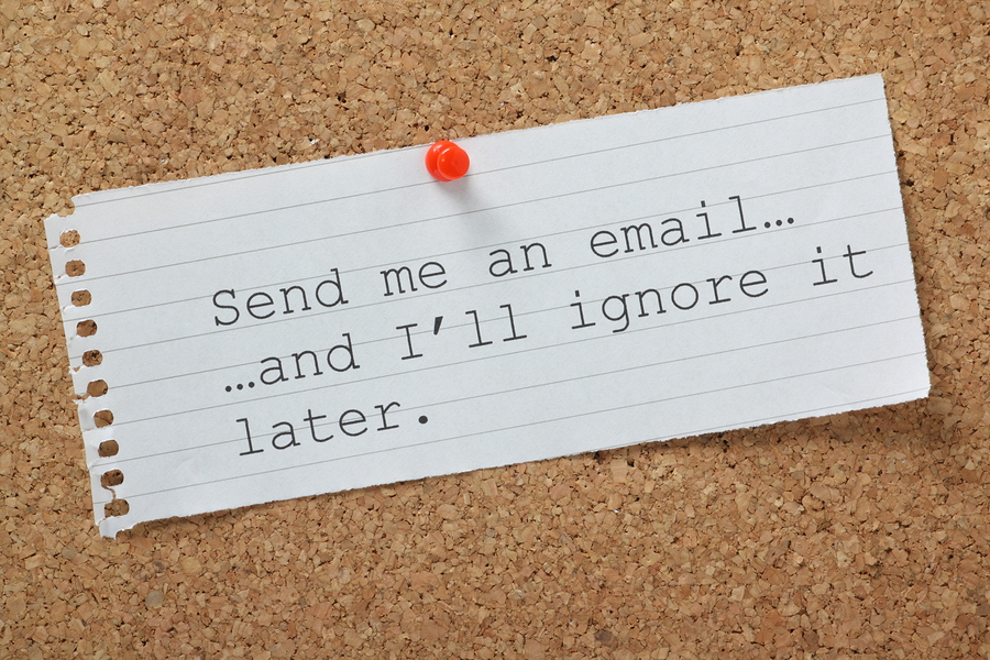 The phrase Send me an email and I'll Ignore it Later on a cork notice board. A concept for time wasting or avoiding being overwhelmed by communications and workload